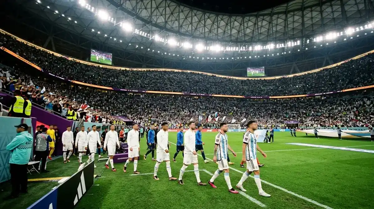 Two international football teams walking out side by side from the tunnel before a major knockout match in a large indoor stadium, one side in white, one in light blue and white stripes