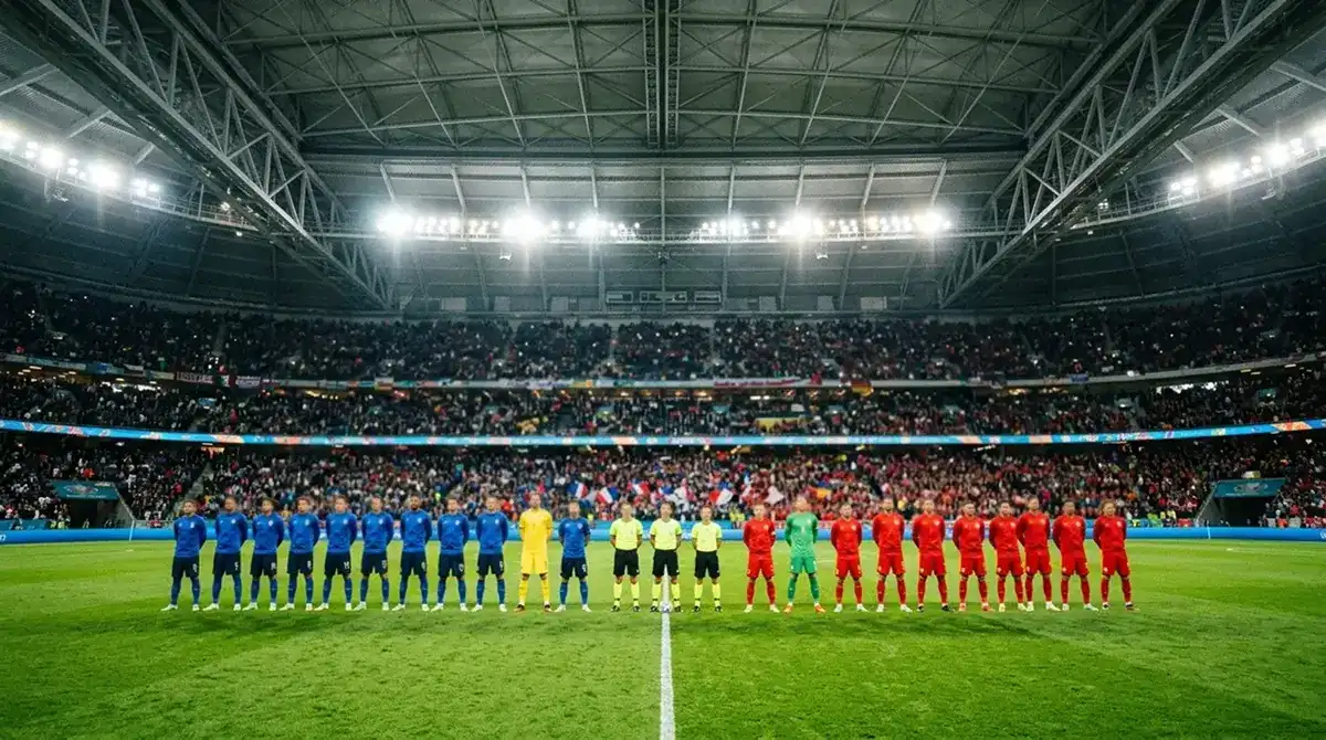 Two international football teams lining up in a floodlit indoor stadium before a major knockout match, one side in blue, one in red, a large crowd blurred behind them